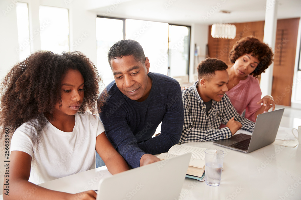 Middle aged black parents helping their teenage kids using laptops to do homework, close up