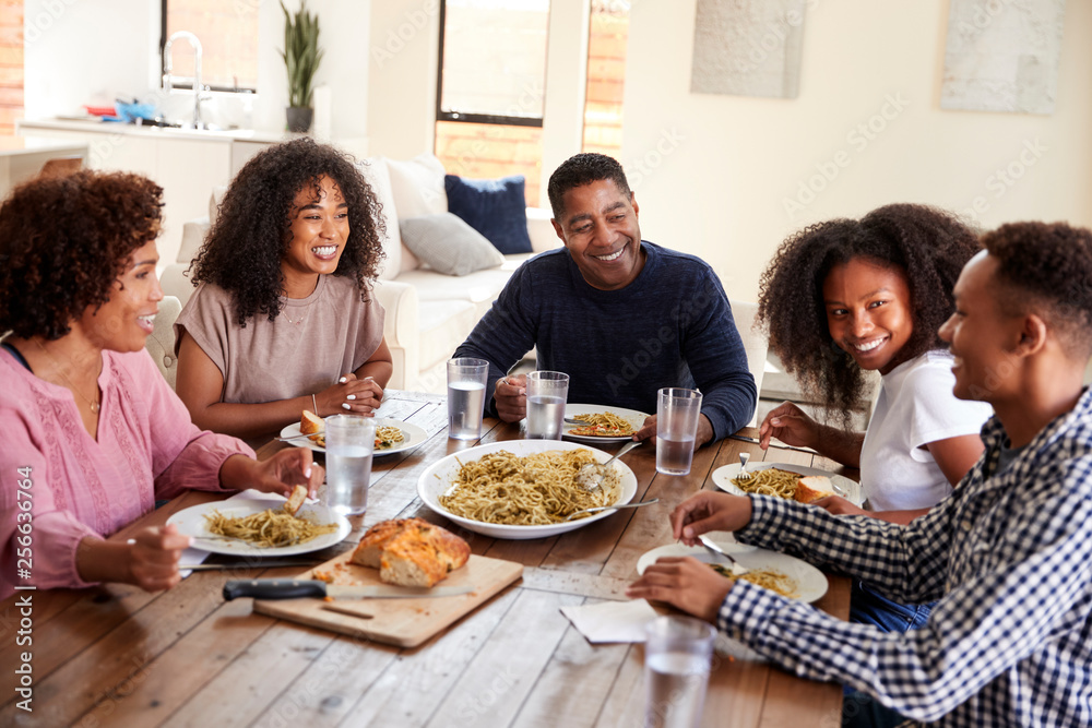 Middle aged black couple sitting at dinner table eating with their children, close up