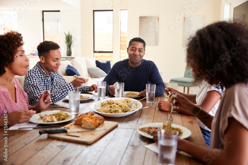 Middle aged black man sitting at the table eating dinner with his wife and family  close up