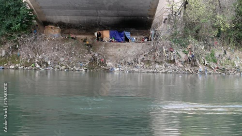 Rome, late evening, Tiber River - homelesses live under an bridge a kayak passes with two rowers