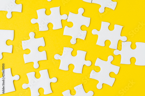 White jigsaw puzzle on solid yellow background metaphor solution to solving business problem, creativity, choice or teamwork concept