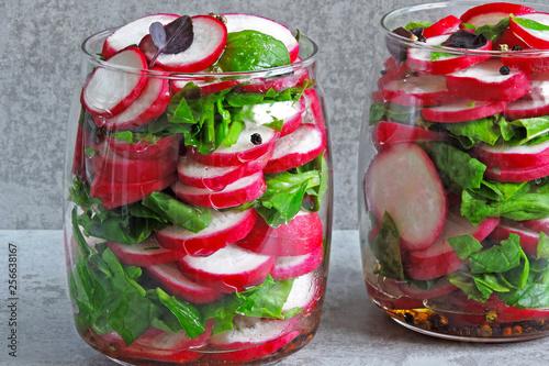 Radish salad with spinach in a jar. Fitness salad in the jar. Fresh radishes and fresh chopped spinach leaves. Vegetable salad in a jar to go.