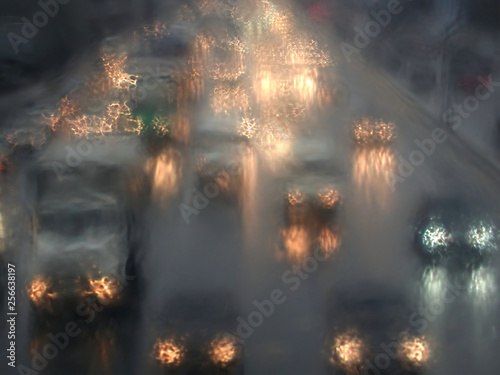 Fototapeta Naklejka Na Ścianę i Meble -  Turned on cars headlights moving in rainy twilight as impressionism stylized