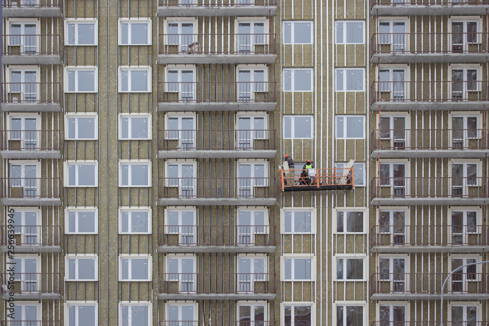 Builder hang in the basket of an unfinished house. Construction of a residential high-rise apartment building