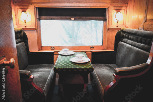 Travelling inside a luxurious vintage train carriage, private room with window view. Tea set served on table