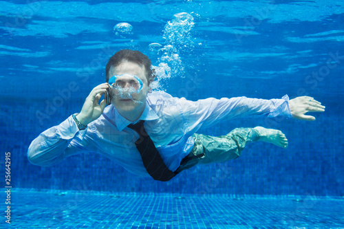 Caucasian businessman talking on a mobile phone underwater