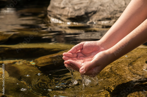 Hands holding clear transparent water from the river