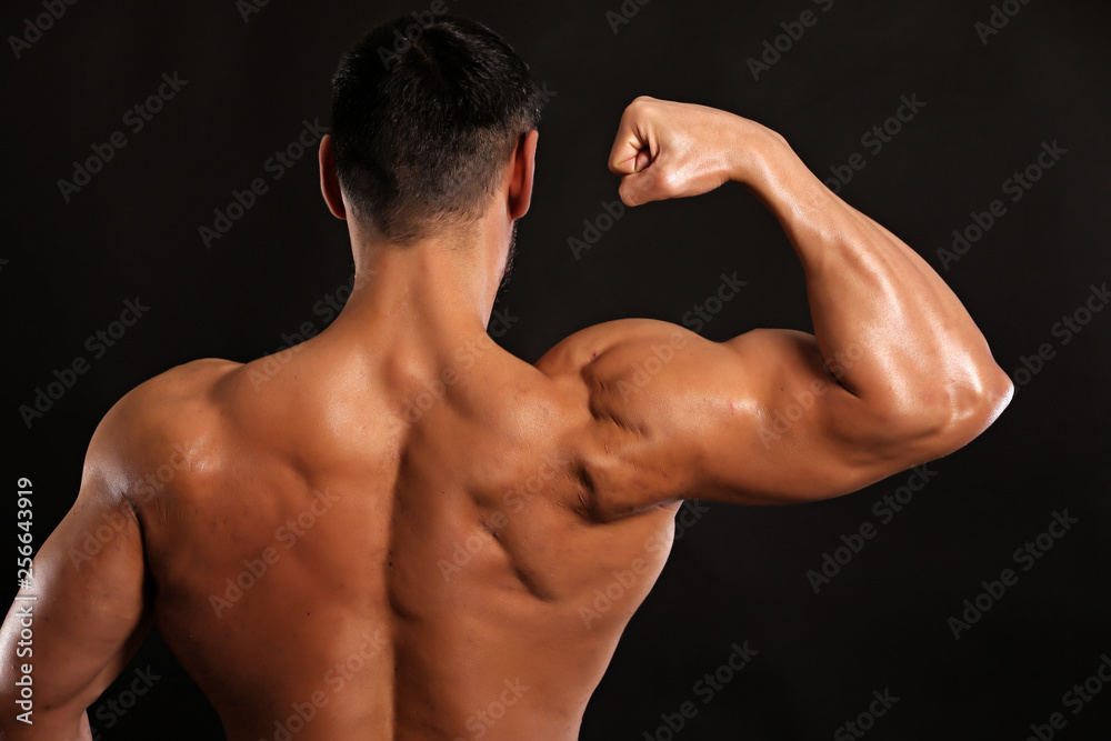 muscular man flexing his muscles on black background and smiling muscular man flexing his muscles on black background and smiling