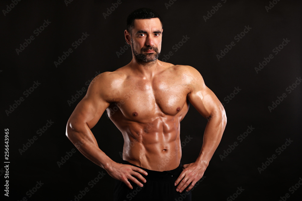 Portrait of young handsome  muscular bodybuilder on black background 