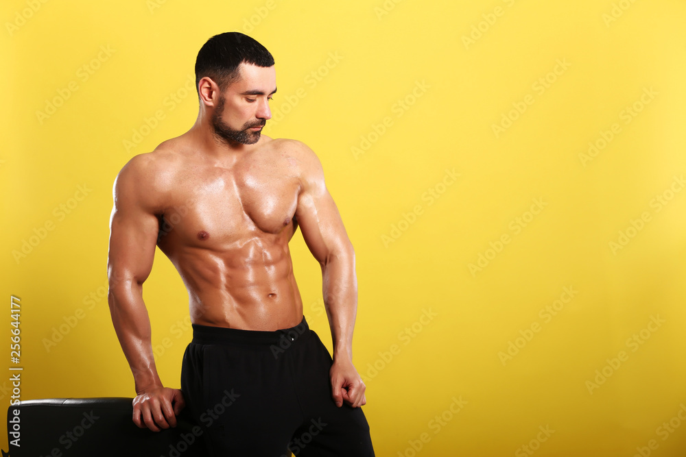 Portrait of young handsome muscular bodybuilder on yellow background Portrait of young handsome muscular bodybuilder on yellow background