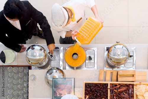 Fotografie Hotel staff testing and refilling orange juice for guest breakfast