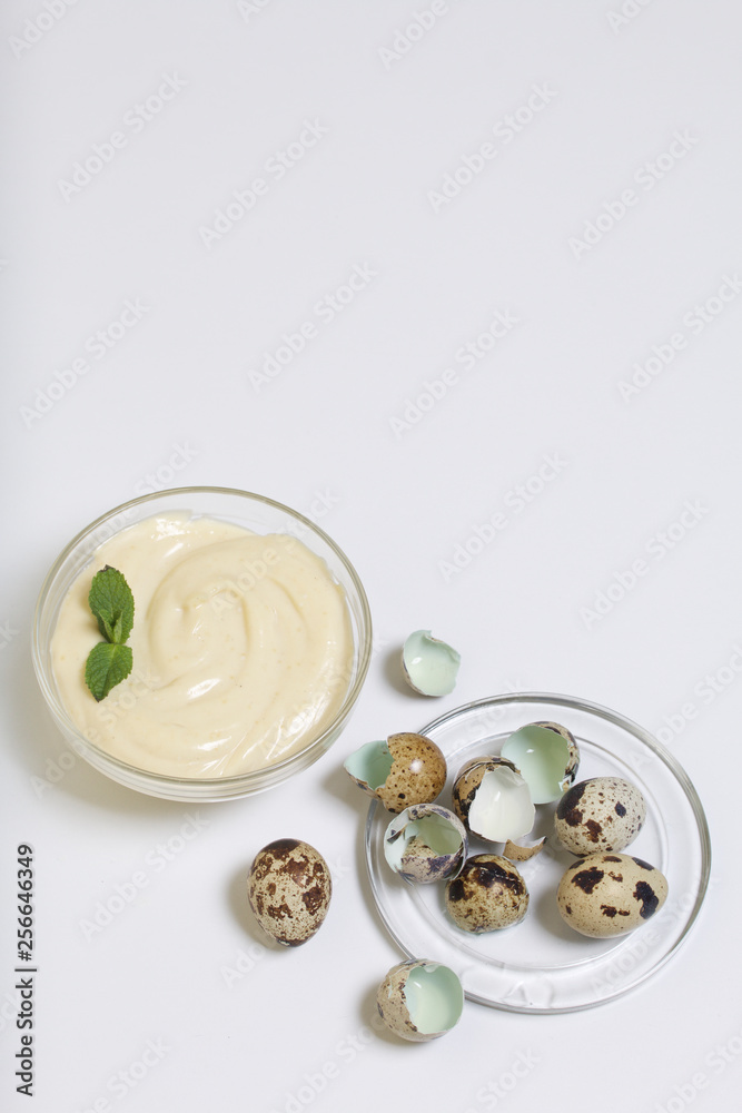 Handmade mayonnaise using quail eggs. In a glass container, decorated with greenery. Near quail eggs and shell from them. On a white background. Handmade mayonnaise using quail eggs. In a glass container, decorated with greenery. Near quail eggs and shell from them. On a white background.