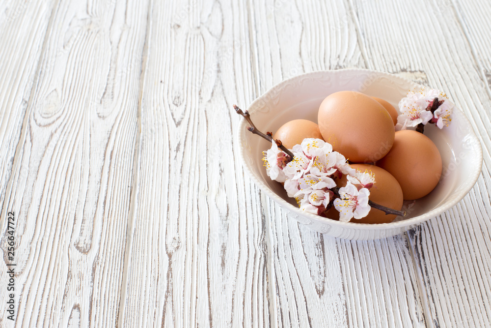 Chicken eggs and flowers in a white bowl Chicken eggs and flowers in a white bowl