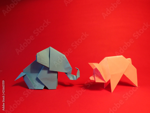 Origami blue elephant and pink pig on a red background