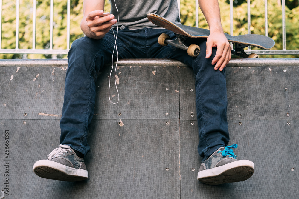 Man hobby. Style and lifestyle. Skateboarding and music relaxation. Guy sitting on ramp with skateboard and media player. Man hobby. Style and lifestyle. Skateboarding and music relaxation. Guy sitting on ramp with skateboard and media player.