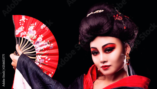 beautiful Japanese girl in kimono with a fan on a black background