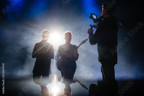 Camera man filming music video clip for musicians in low light