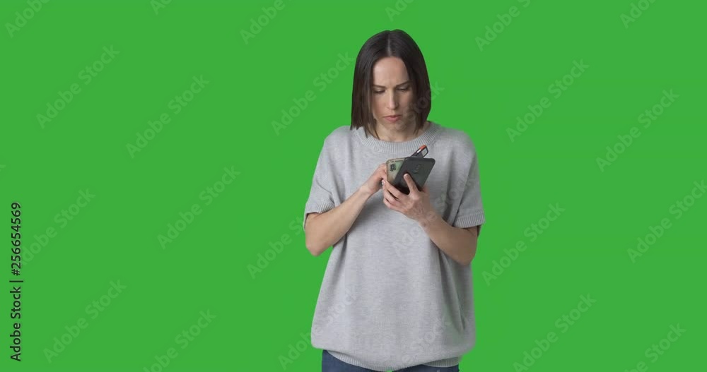 Young woman calling and text messaging using three different mobile phones over green background Young woman calling and text messaging using three different mobile phones over green background
