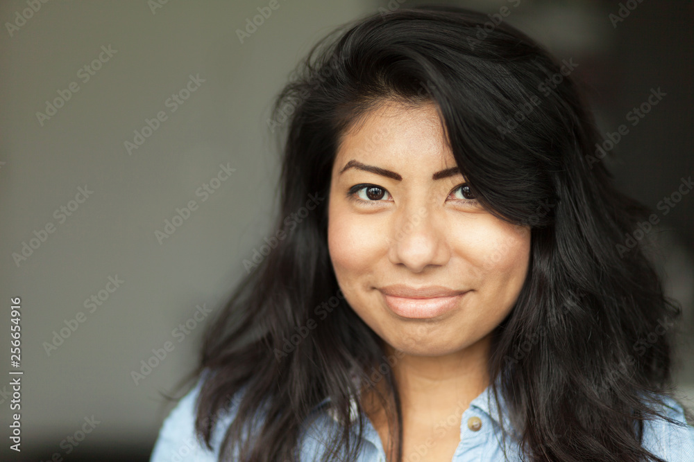 Portrait of a Smiling young Spanish woman. She is happy isolated on gray Portrait of a Smiling young Spanish woman. She is happy isolated on gray