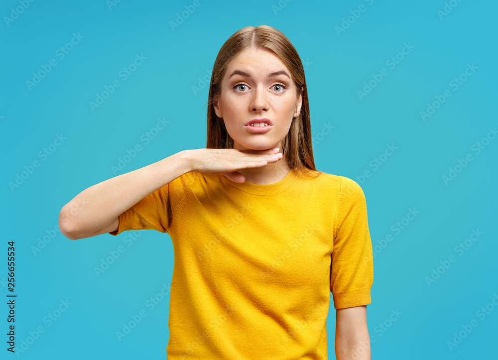 I am fed up with it. Furious young girl in yellow sweater touching her neck with hand and grimacing on blue background I am fed up with it. Furious young girl in yellow sweater touching her neck with hand and grimacing on blue background
