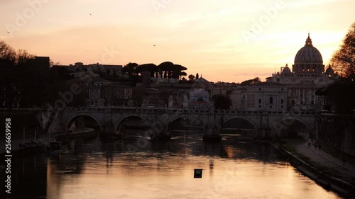 Rome, dramatic orange sunset behind the Vatican Dome with the Tiber river and birds