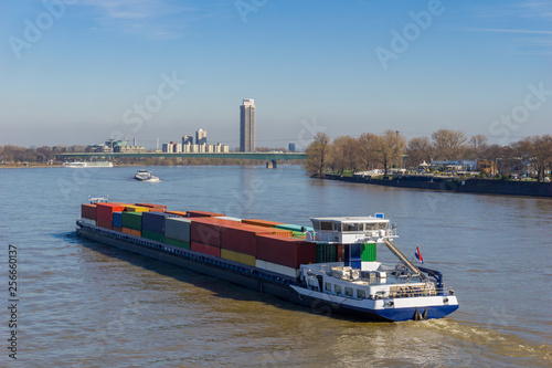 Riesiges Containerschiff mit vielen großen Containern fährt durch den Rhein in Köln.