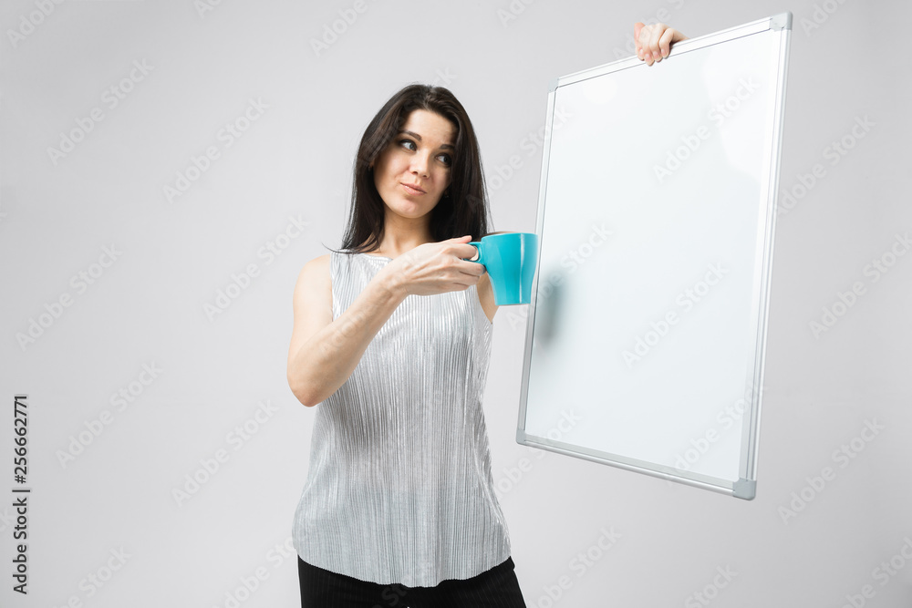 Portrait of brunet smiling woman in blouse holding a blue cup and board Portrait of brunet smiling woman in blouse holding a blue cup and board