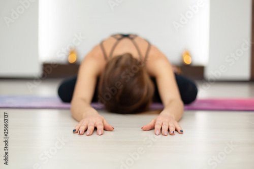 Young woman practicing yoga stretching in gym. Fit and wellness lifestyle
