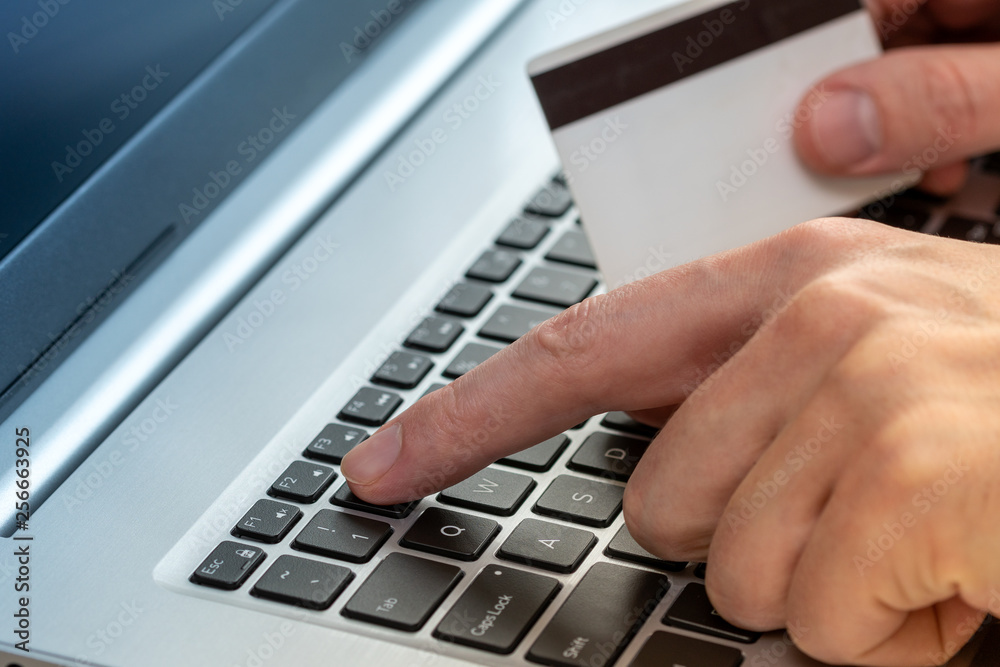 Hands holding credit card and using laptop Hands holding credit card and using laptop
