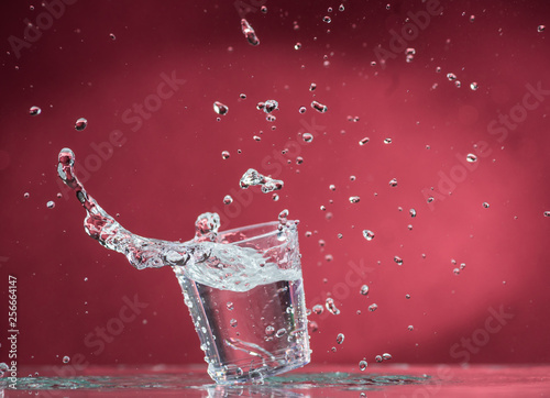 falling small glasses and spilling water on a red background