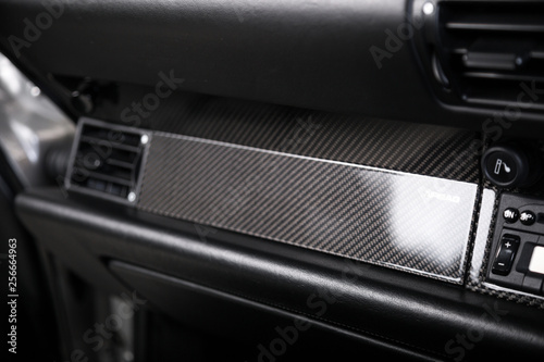 Close up of closed storage compartment in car with carbon fibre trim