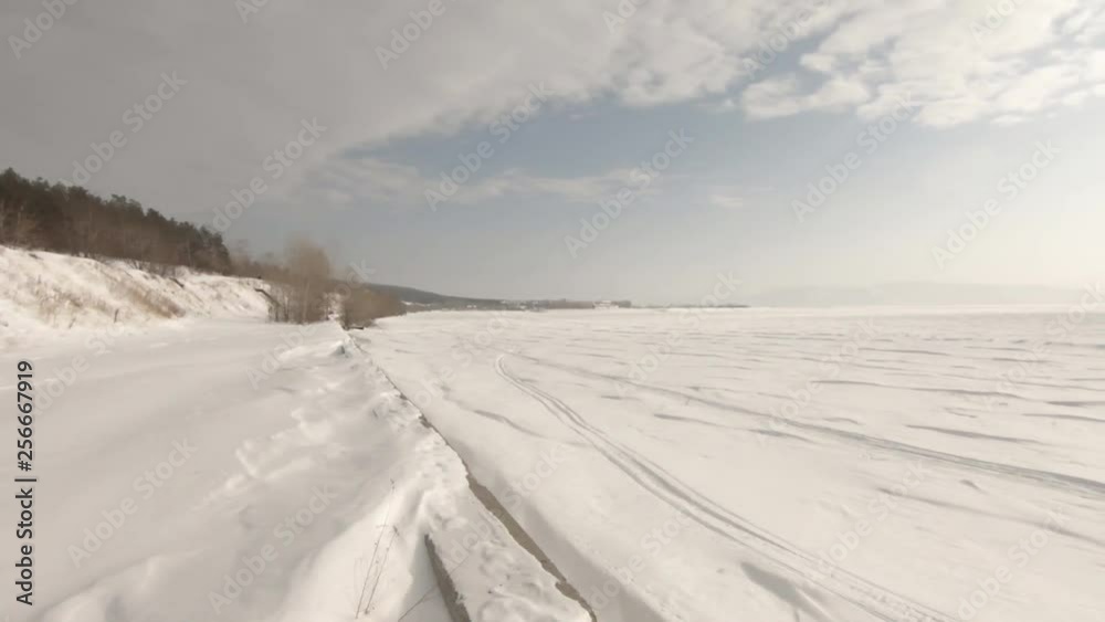On the horizon of the mountain. Frozen river and a lot of snow. Backlight and bright sun. Slow camera wiring. On the horizon of the mountain. Frozen river and a lot of snow. Backlight and bright sun. Slow camera wiring.