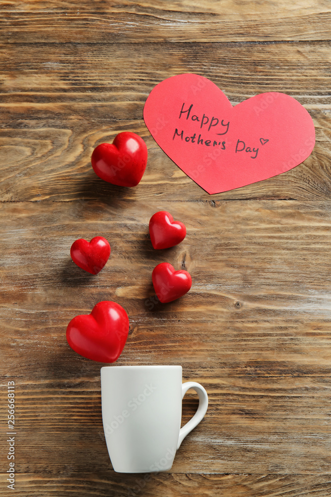 Cup with hearts and greeting card for Mother's Day on wooden table Cup with hearts and greeting card for Mother's Day on wooden table