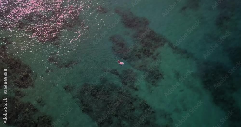 Aerial drone video of person snorkeling in the clear blue ocean off the coast of Maui from sandy beach