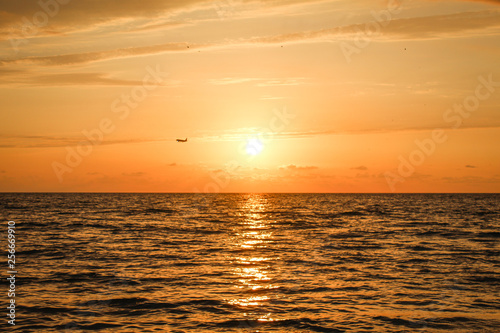 Golden  Fiery sunset on the Black Sea  on the beach. Coast  stones  waves  sun  beautiful sky  clouds. August  Batumi  Georgia. Water  ease  game. plane in the sky  tourism