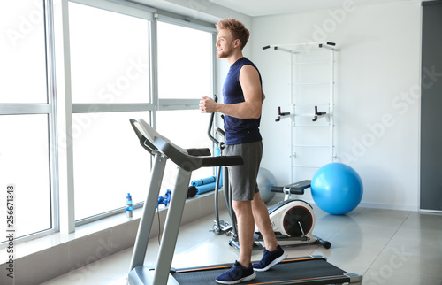 Sporty young man training on treadmill in gym