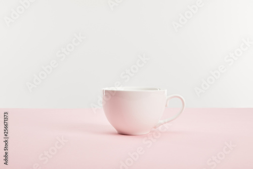 white cup with drink on pink surface isolated on grey