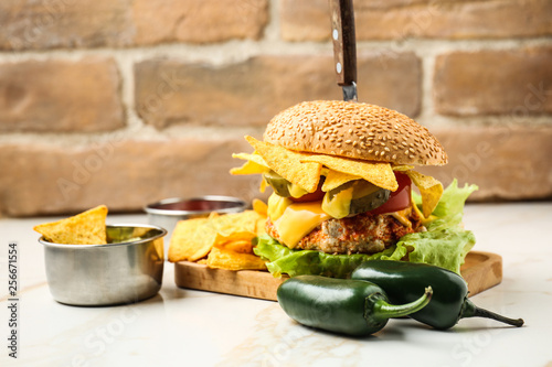 Tasty burger with nachos and guacamole on table photo