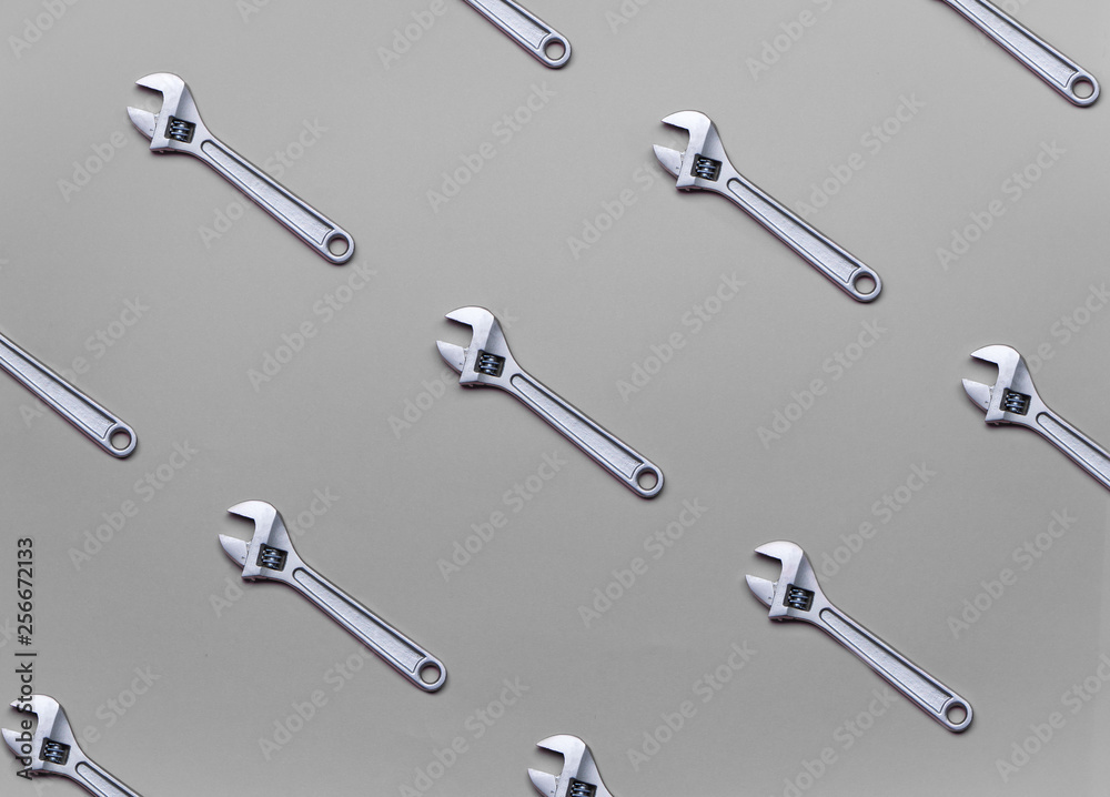 The pattern of adjustable wrenches on a gray background. The pattern of adjustable wrenches on a gray background.