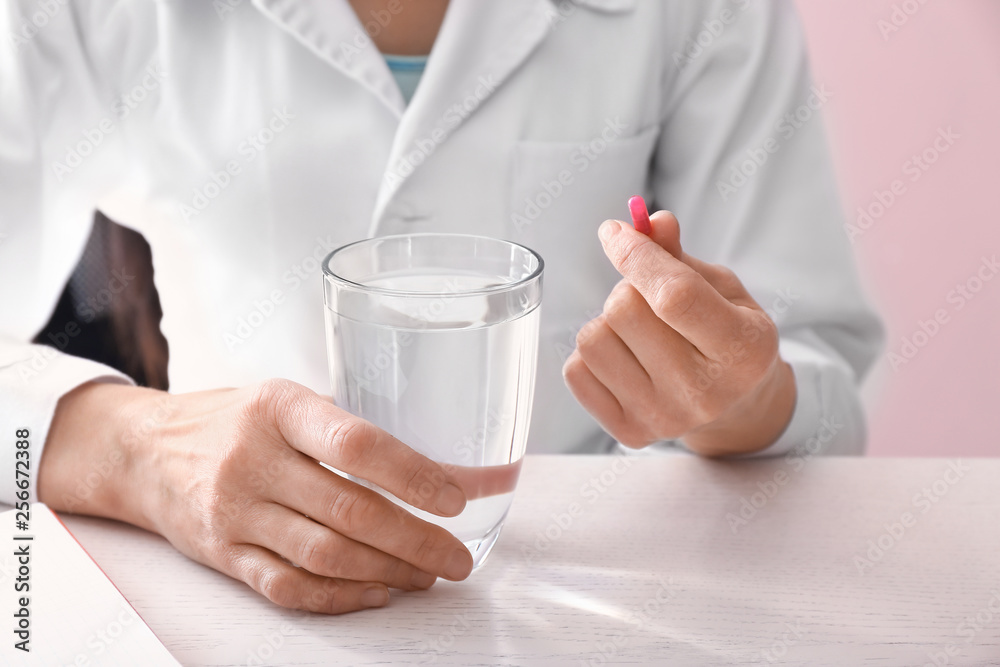 Doctor with pill and glass of water at table Doctor with pill and glass of water at table