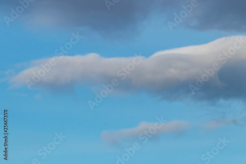 Spring evening sky background with white and grey cumulus clouds on warm sunset