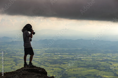 Silhouette man taking photo on top of a Mountain. 