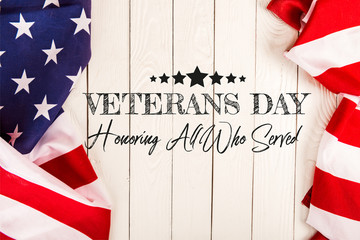 Top view of American flags and veterans day lettering on white wooden surface
