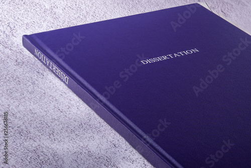 closed book in blue cover with the name Dissertation on the table close-up