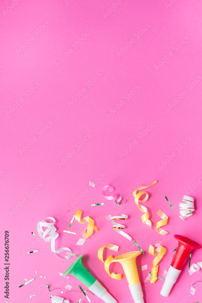 Colorul party streamers on pink background. Celebration concept. Flat lay.