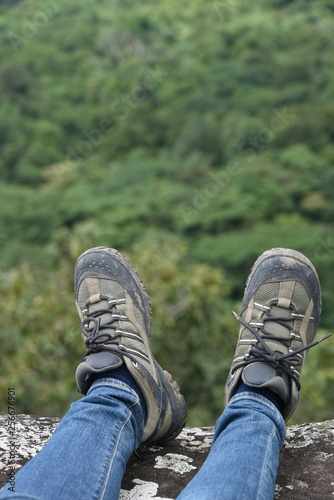 Adventure & outdoor activity concept : The part of trekking shoes with forest background 