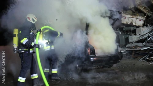 firefighter extinguish a carfire with water huge flames photo