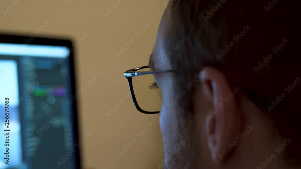 Close up video editor wearing blue light blocking glasses whilst working