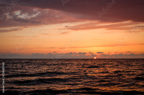 Golden, Fiery sunset on the Black Sea, on the beach. Coast, stones, waves, sun, beautiful sky, clouds. August, Batumi, Georgia. Water, lightness, play. Pink, lilac, crimson