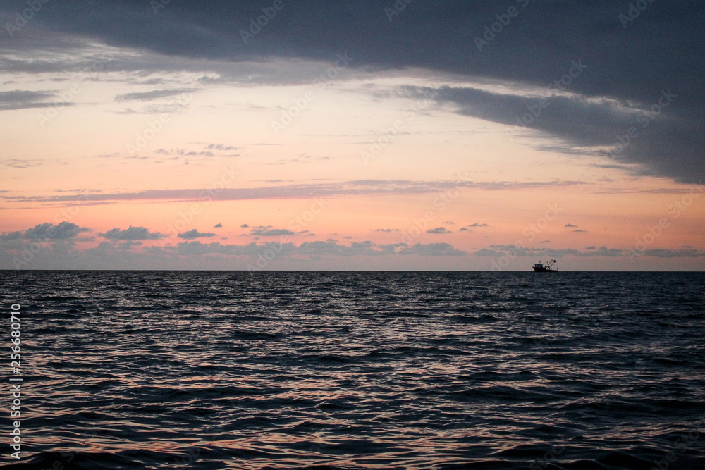 Golden, Fiery sunset on the Black Sea, on the beach. Coast, stones, waves, sun, beautiful sky, clouds. August, Batumi, Georgia. Boat, ship. Water, lightness, play. Pink, lilac, crimson